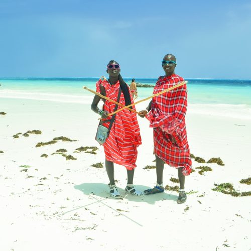 Zanzibar, Kiwengwa - 15 January, 2015: two young masai men in their original red clothes stood still for a moment, on the local beach of Kiwengwa