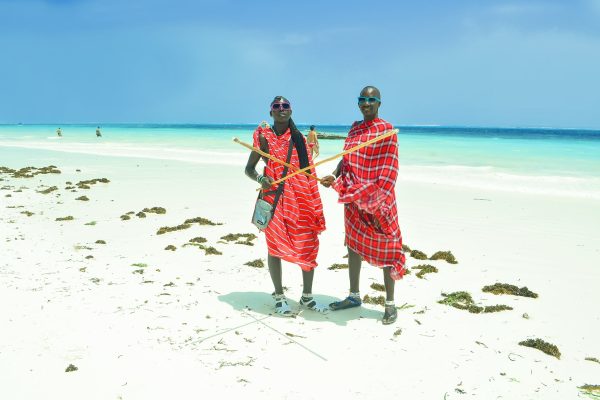 Zanzibar, Kiwengwa - 15 January, 2015: two young masai men in their original red clothes stood still for a moment, on the local beach of Kiwengwa