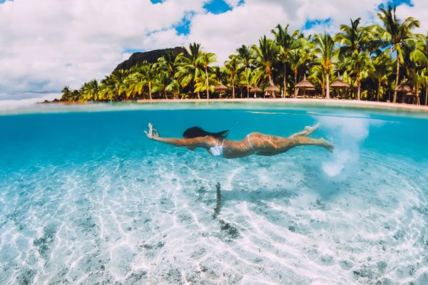 Attractive woman swimming underwater in transparent blue ocean at Mauritius, Le Morne